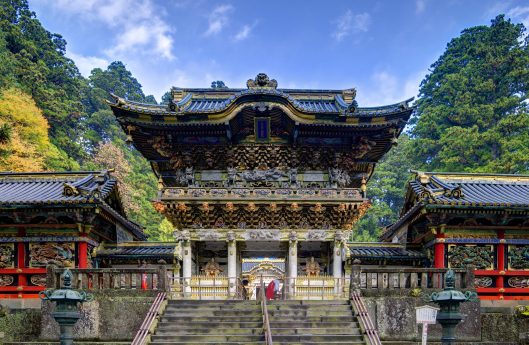 Nikko, Japan - November 1, 2012: A shinto priest sweeps under the Yomeimon gate at Tosho-gu Shrine. Founded in 1617, the remains of the first shogun Tokugawa Ieyasu are entombed here.